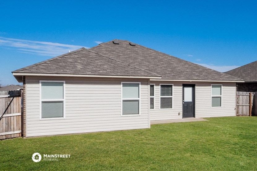 a white house with a grey roof and a yard