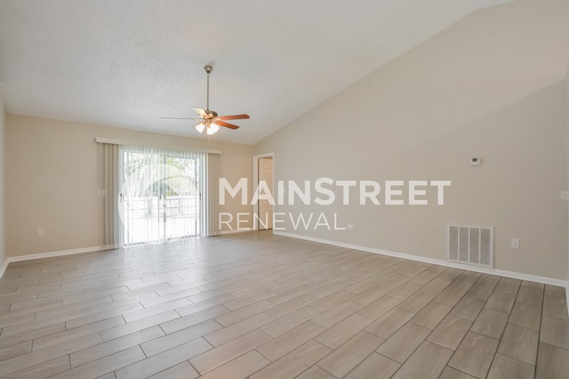 a spacious living room with wood floors and a ceiling fan