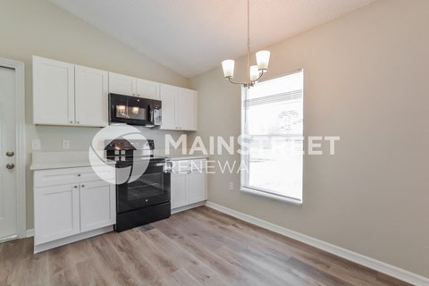 a kitchen with white cabinets and a black stove and a window