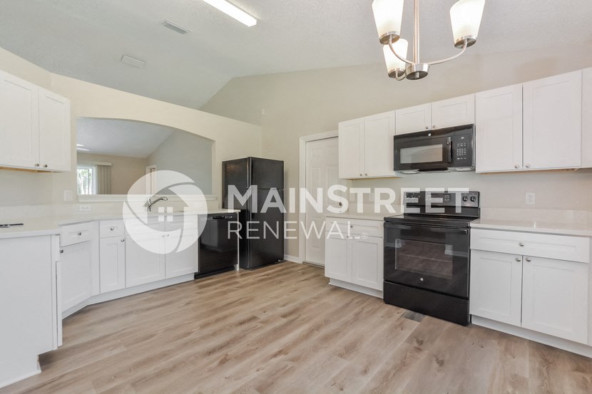 a renovated kitchen with white cabinets and black appliances
