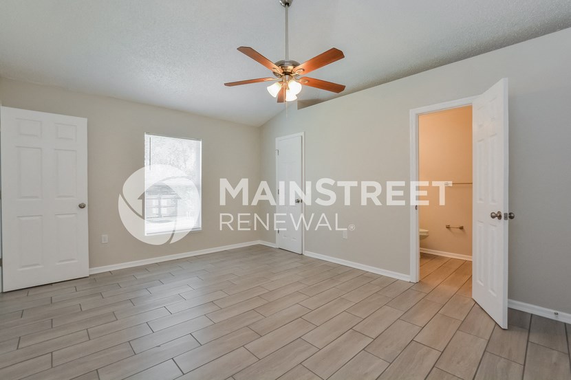 a large living room with wood floors and a ceiling fan