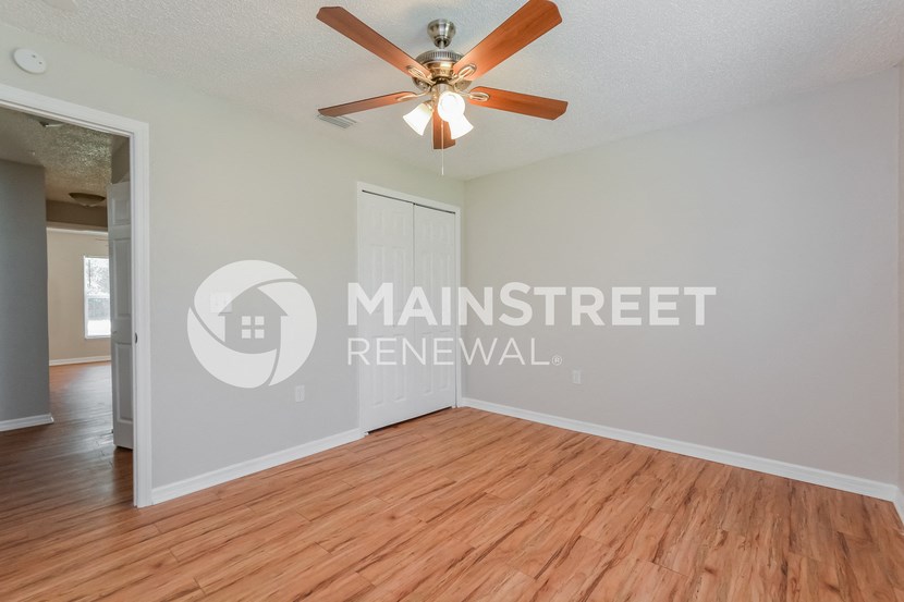 a renovated living room with wood floors and a ceiling fan