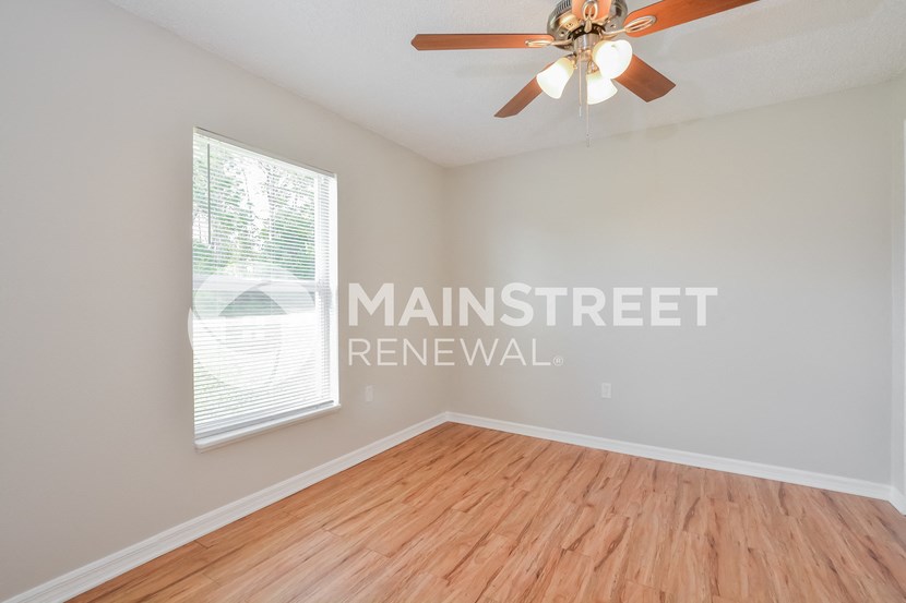 an empty living room with wood floors and a ceiling fan