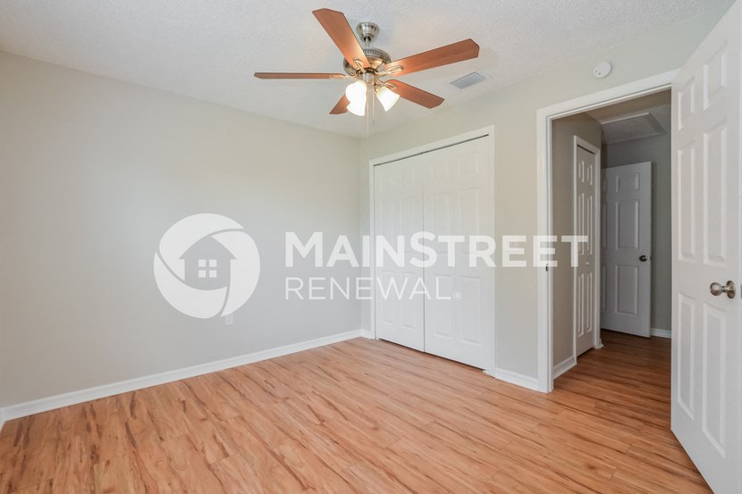 a bedroom with a hard wood floor and a ceiling fan