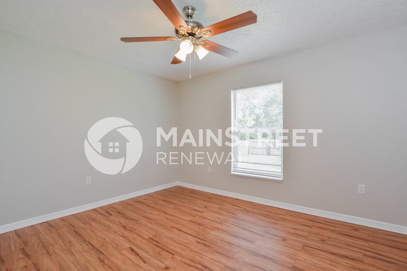 an empty living room with a ceiling fan and wood floors