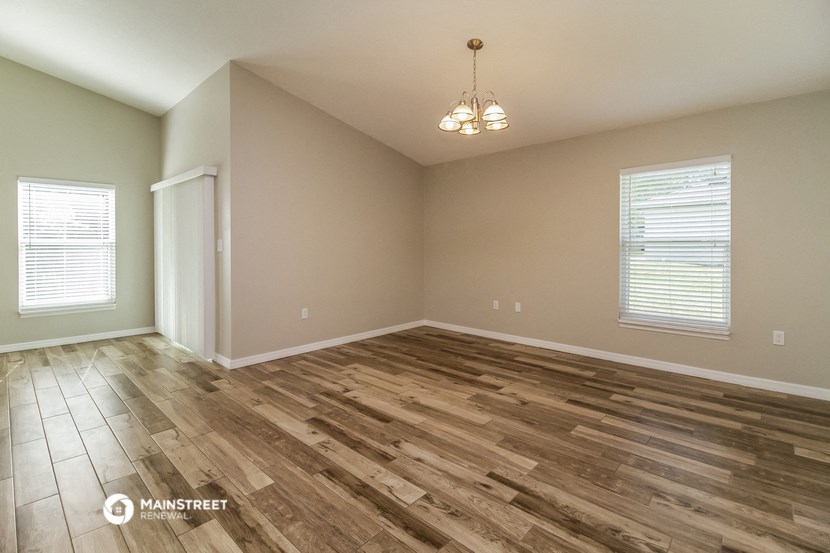 the spacious living room with wood flooring and a chandelier