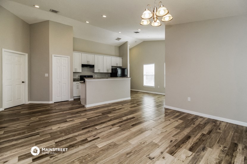 the spacious living room and kitchen with wood flooring