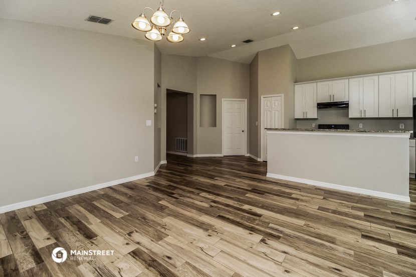 an empty living room and kitchen with wood flooring