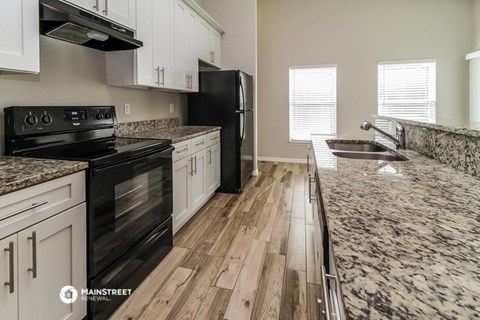 an updated kitchen with marble counter tops and black appliances