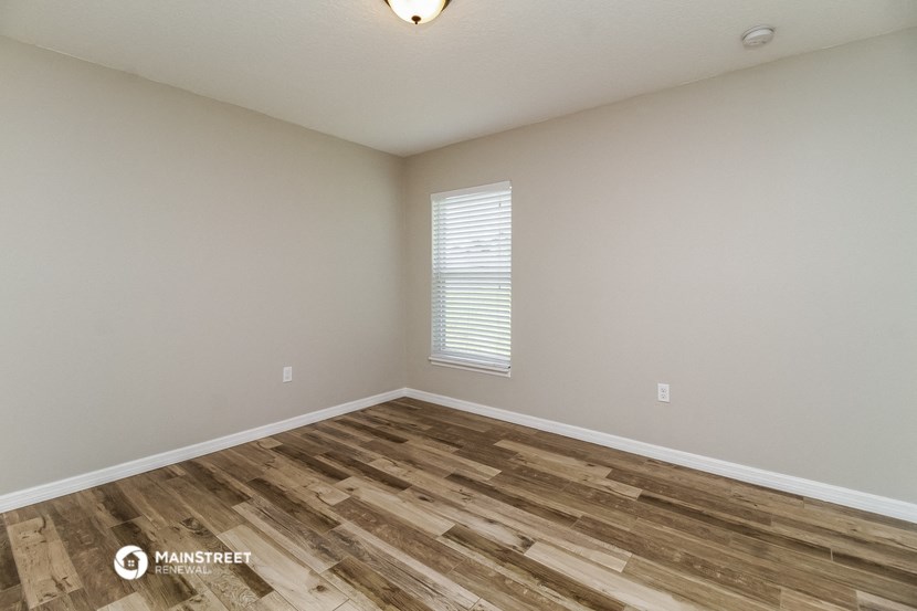 the spacious living room with wood flooring and a window