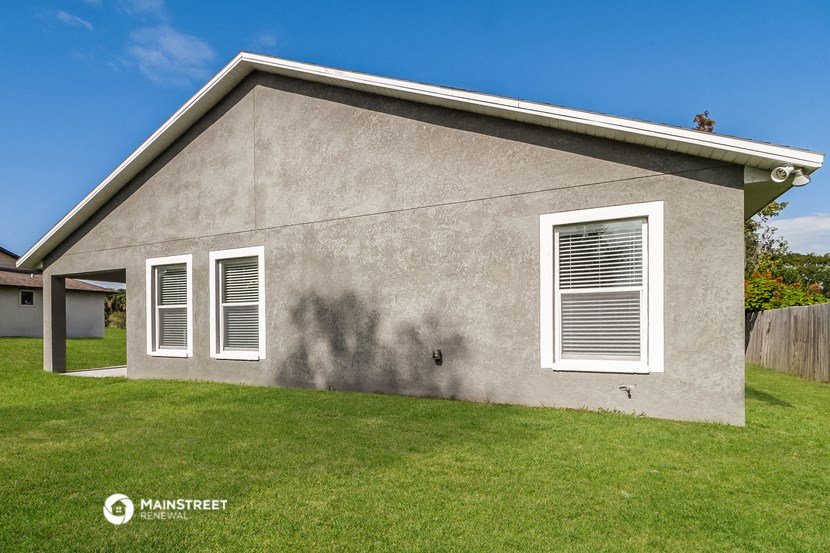 a side view of a house with two windows and a lawn