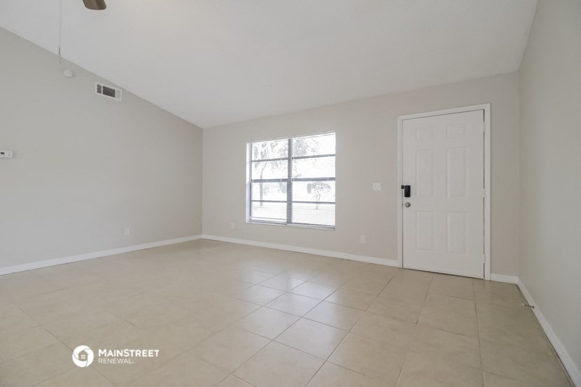 an empty living room with a white door and tiled floors