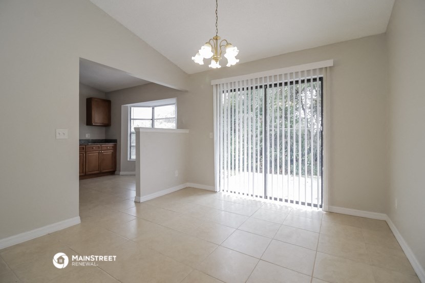 an empty living room with a sliding glass door to a kitchen