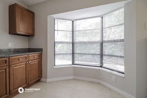 a kitchen with a large window and wooden cabinets