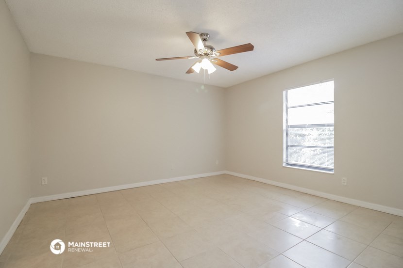 an empty living room with a ceiling fan and tiled floors