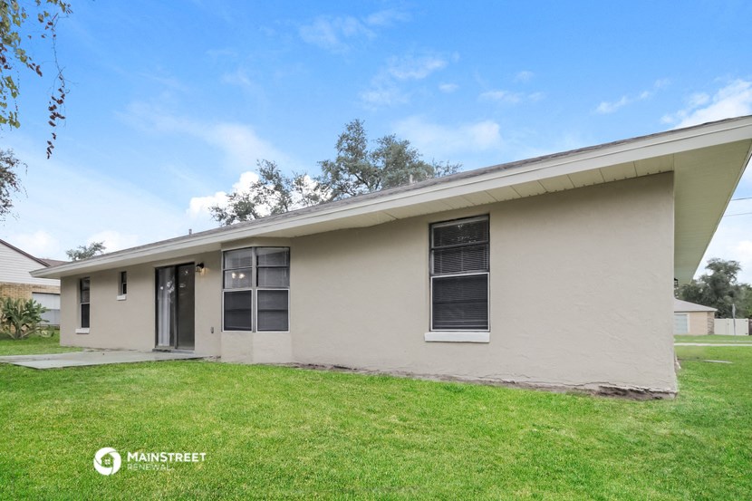 the front of a house with a green lawn and a blue sky