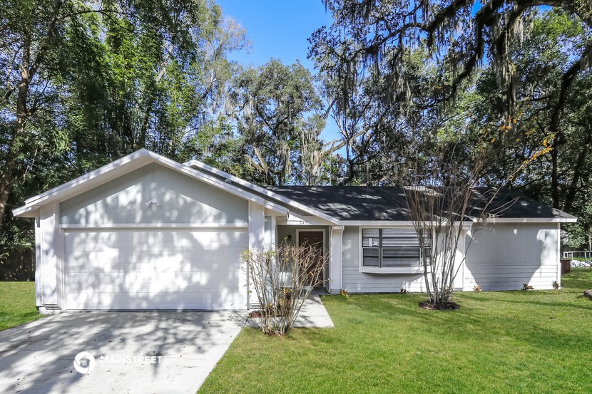 a white house with a lawn and trees