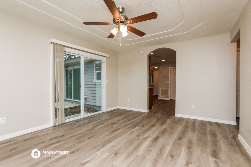 an empty living room with a ceiling fan and a window