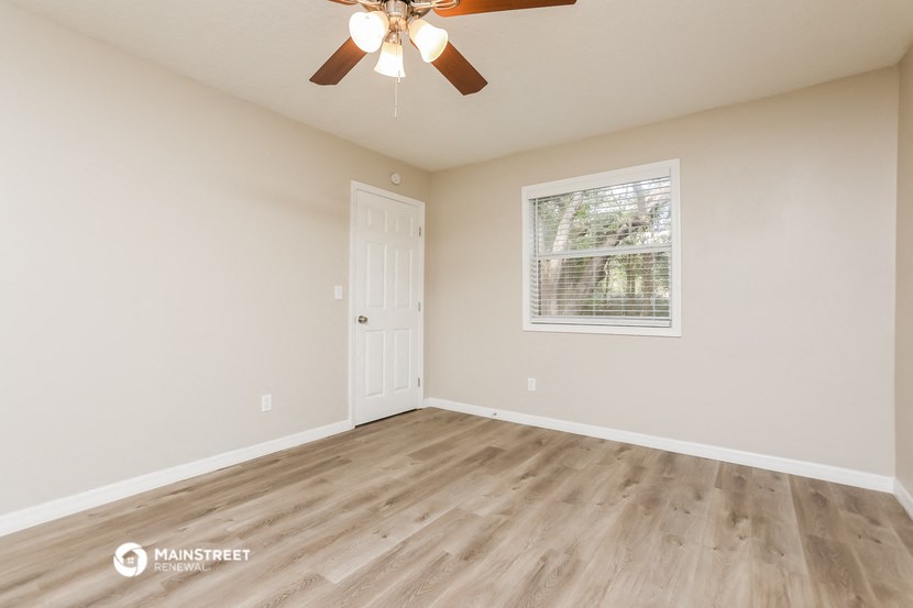 the spacious living room with hardwood floors and a ceiling fan