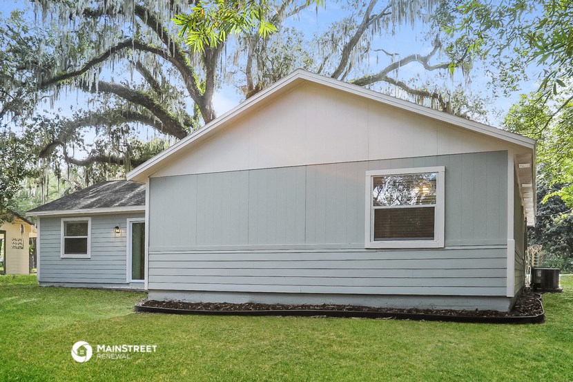the exterior of a gray house with a yard and a tree