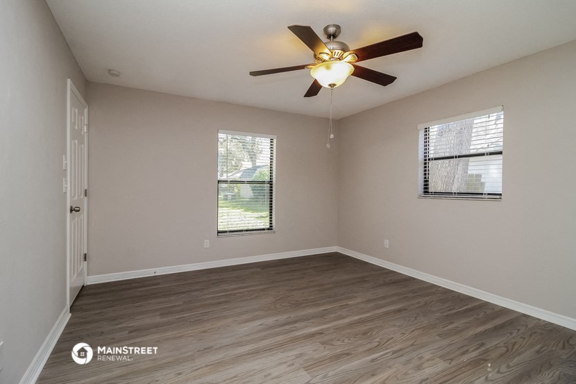 the spacious living room with a ceiling fan and wood flooring