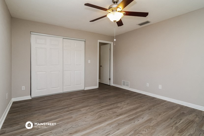 the spacious living room with a ceiling fan