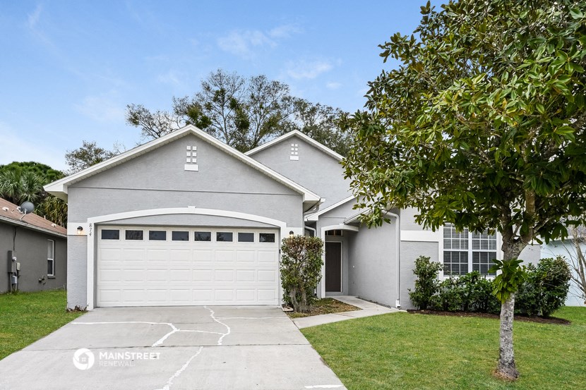 a white house with a garage door and a tree