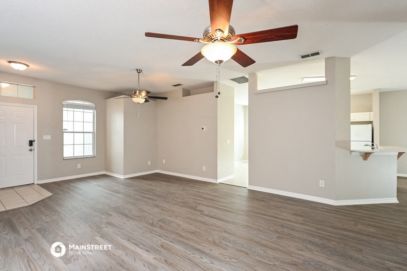 an empty living room with a ceiling fan
