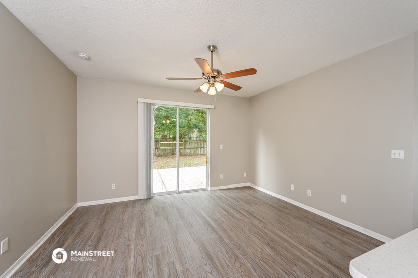 an empty living room with a ceiling fan and a sliding glass door