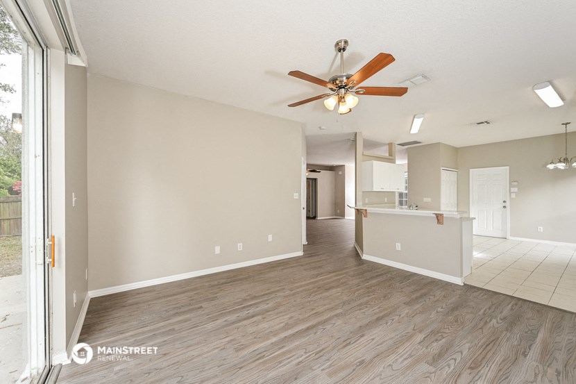 an empty living room and kitchen with a ceiling fan