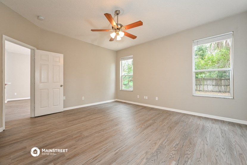 an empty living room with a ceiling fan and a door