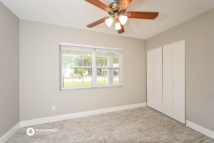 an empty bedroom with a ceiling fan and a window