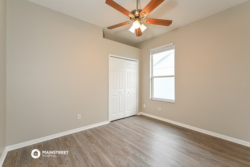 an empty living room with a ceiling fan and a window