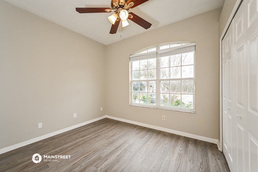 an empty bedroom with a ceiling fan and a window
