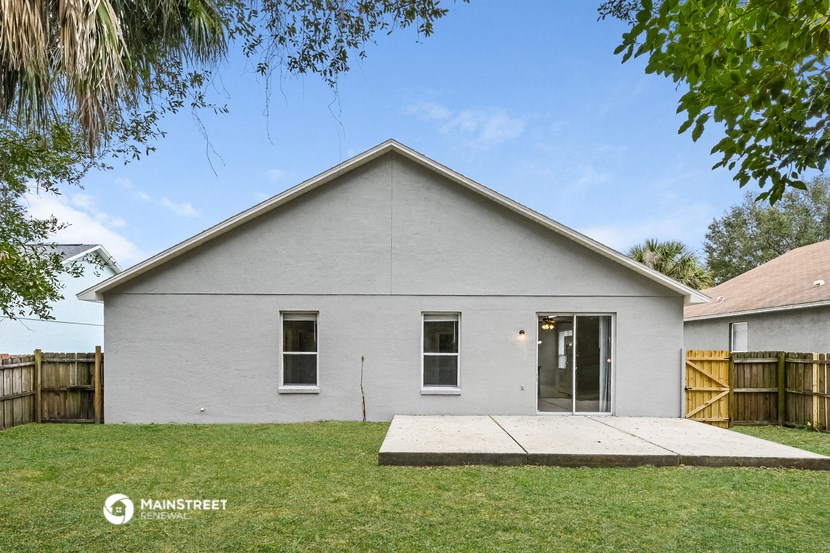 the front of a white house with a sidewalk and grass