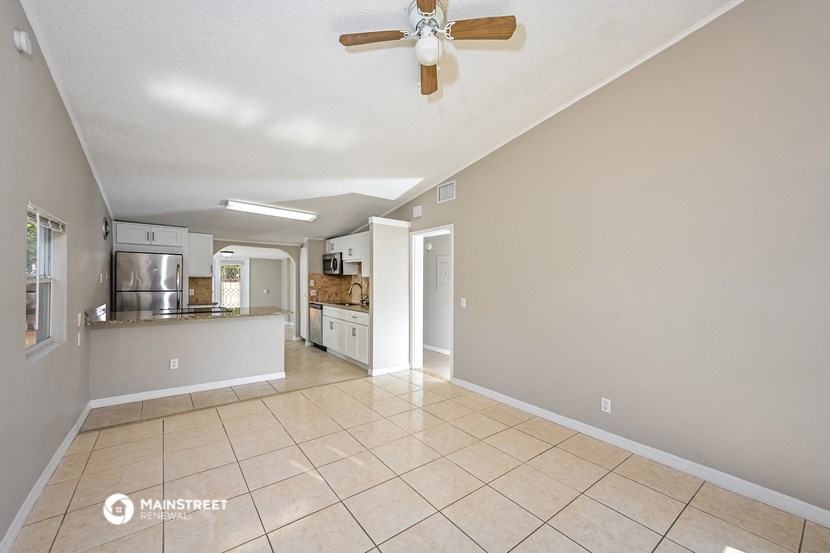 an open kitchen and living room with tile flooring and a ceiling fan