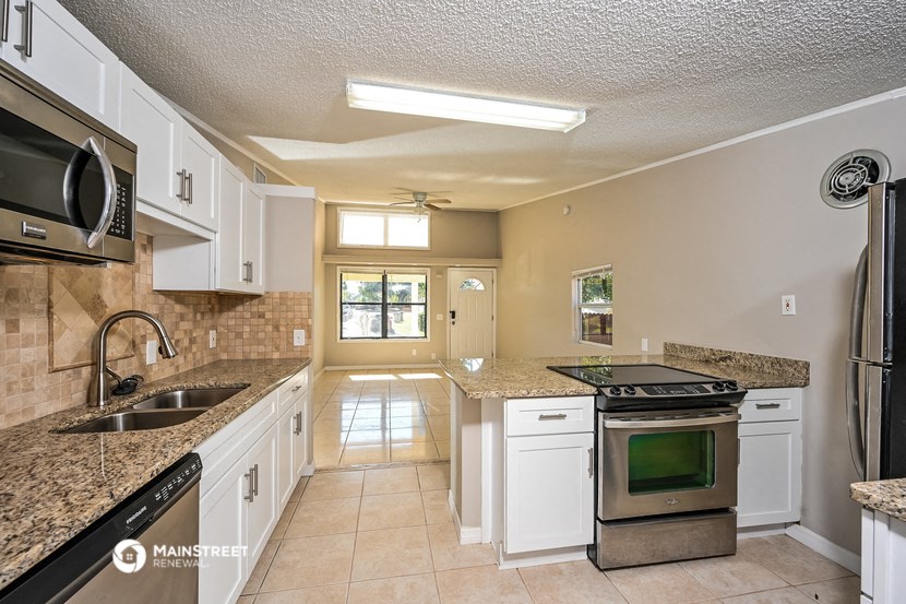 a kitchen with white cabinets and granite counter tops