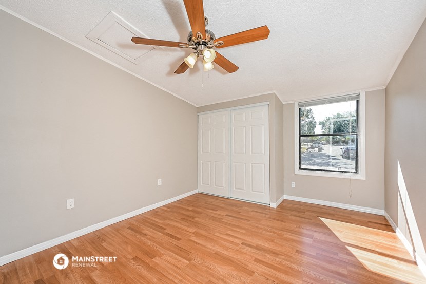 an empty living room with a ceiling fan and a window