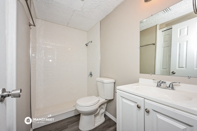 a bathroom with a toilet sink and shower and a mirror
