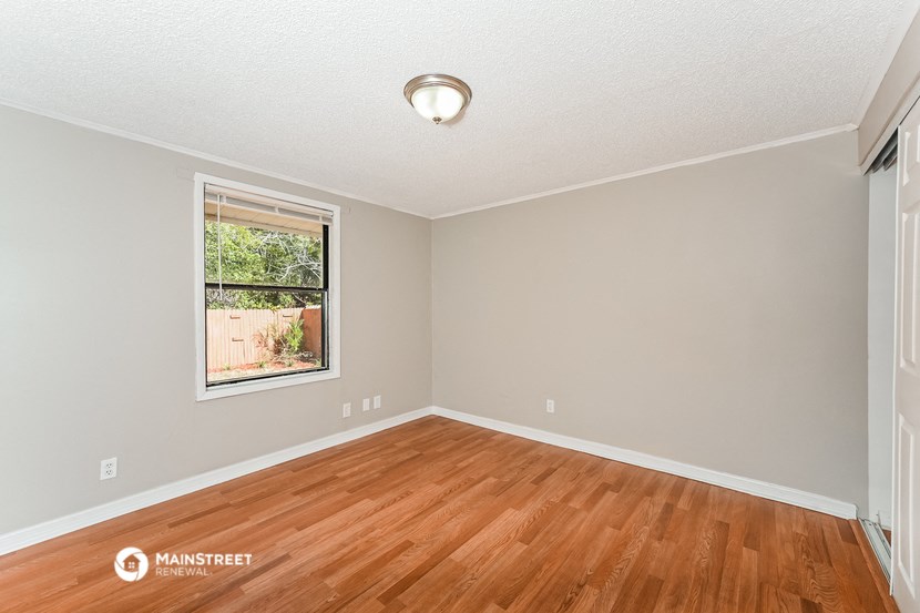 the spacious living room with hardwood flooring and a window