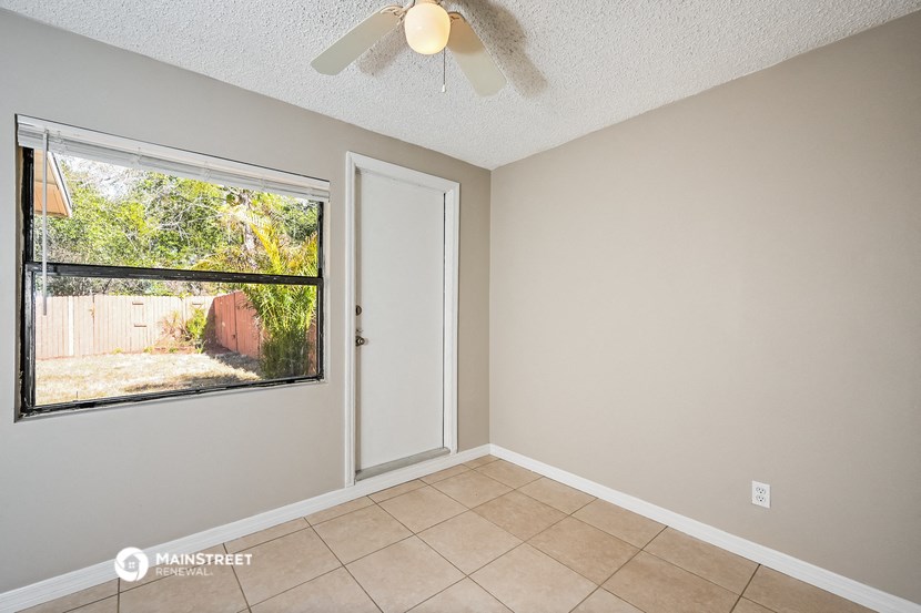 a living room with a large window and a ceiling fan