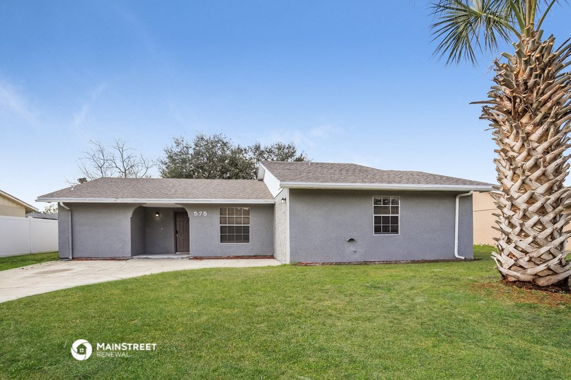 a white house with a yard and a palm tree