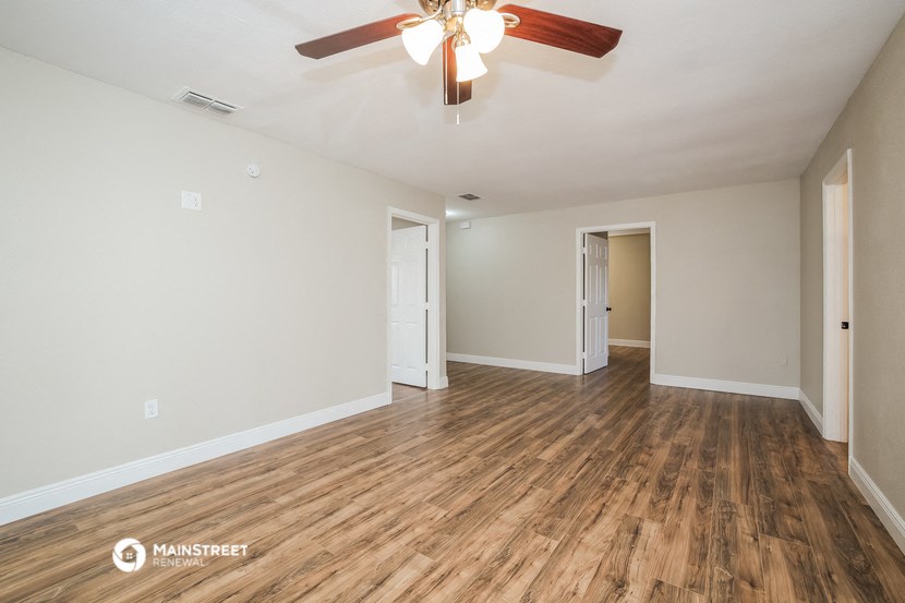 the living room of an empty house with wood flooring and a ceiling fan