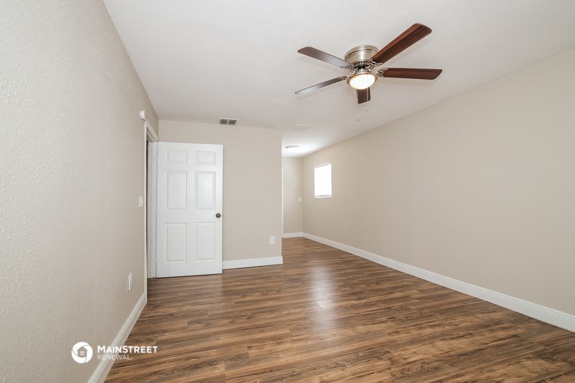 the spacious living room with ceiling fan and hardwood flooring