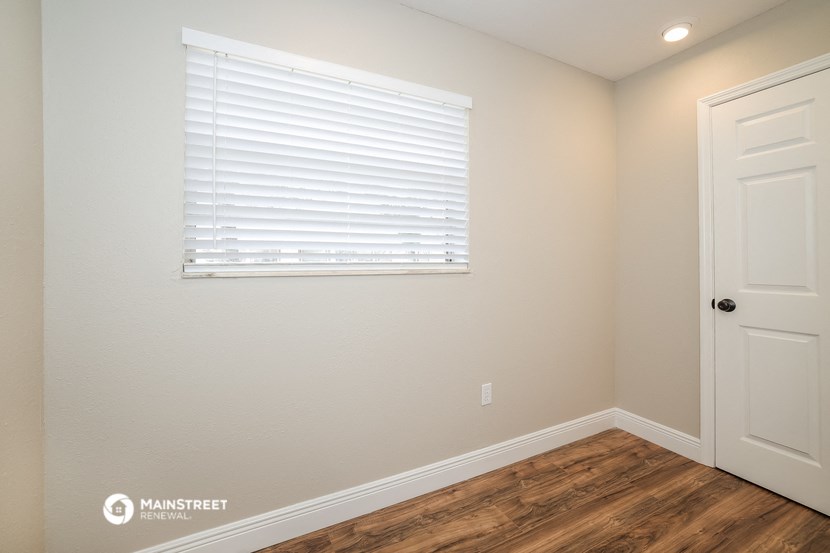 the interior of a bedroom with wood flooring and a window