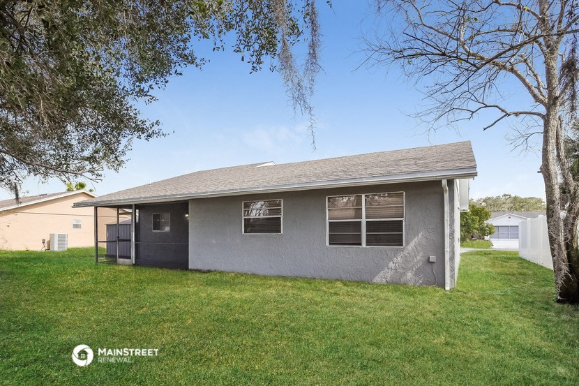 a small gray house with a yard and trees