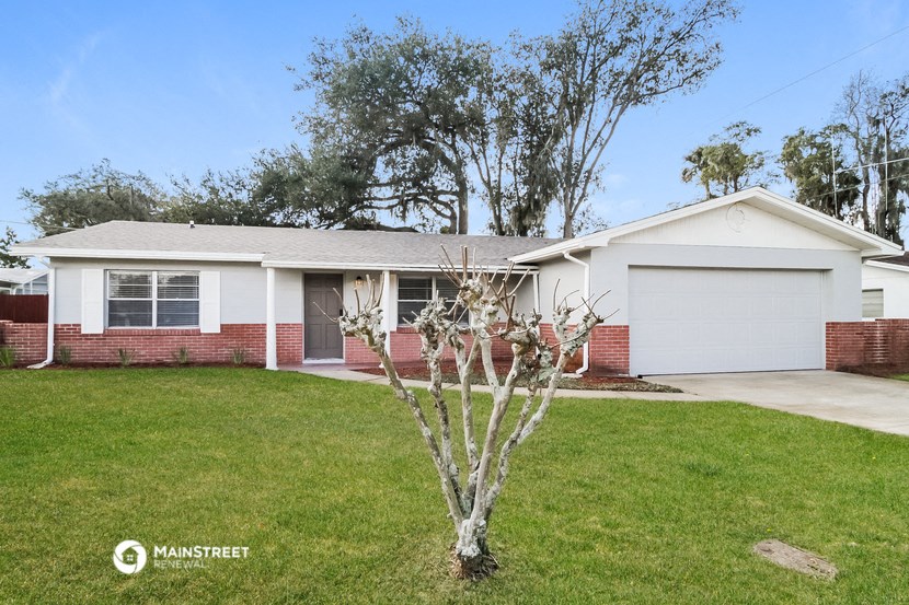 a white and brick house with a lawn and a tree