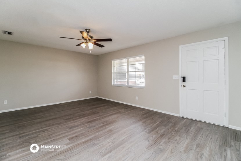 the living room of an empty house with a ceiling fan