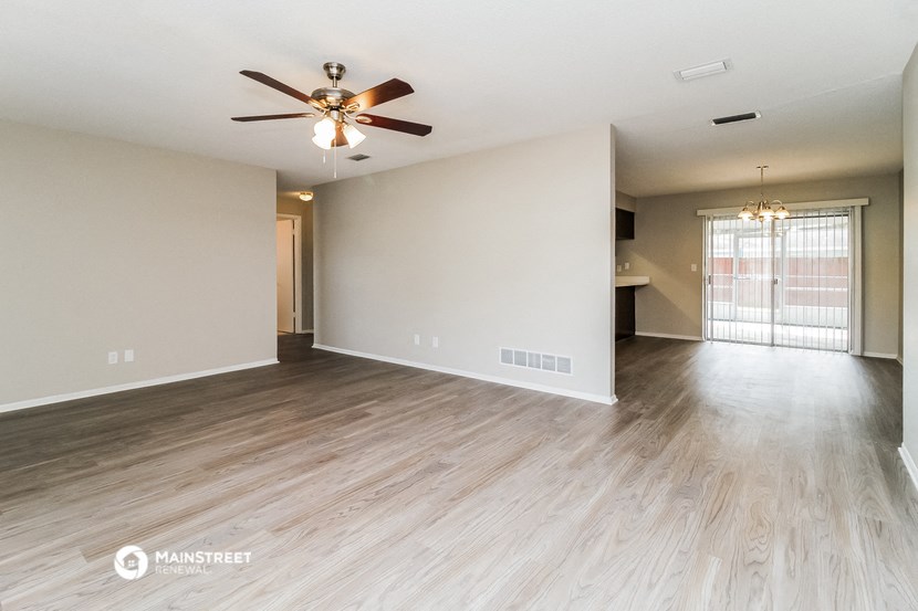 the living room and dining room of an empty house with a ceiling fan