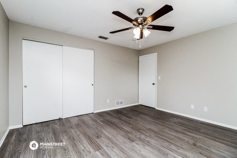 the spacious living room with laminate flooring and a ceiling fan